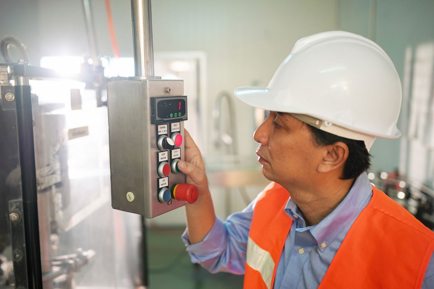 worker controlling the work of machine in production line at beverage industry. Manufacturing operator using digital control panel for real-time production data collection