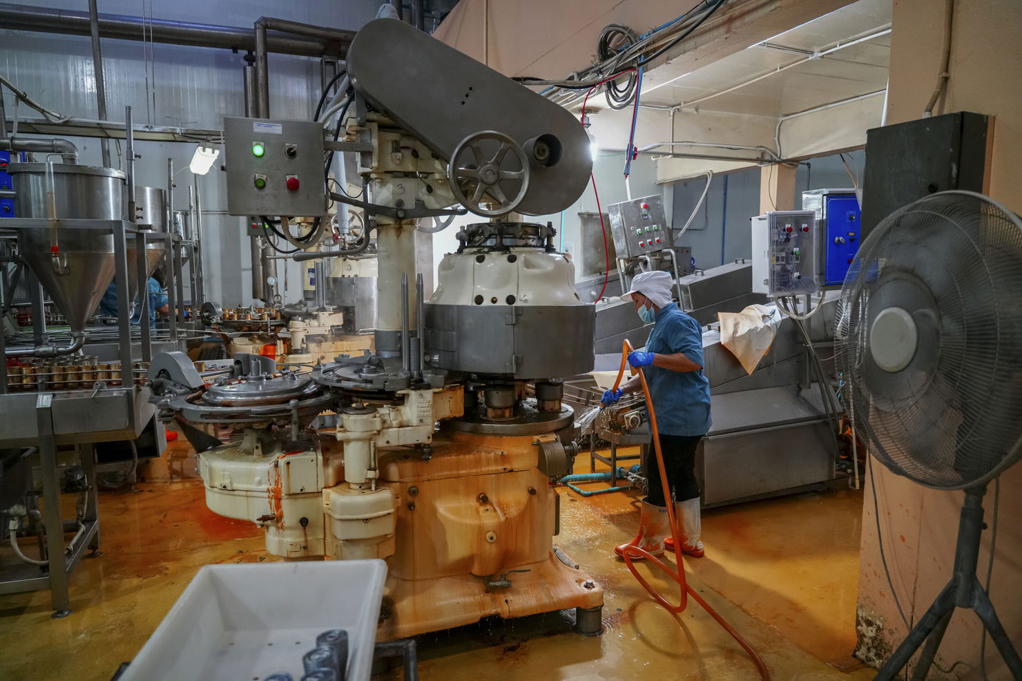 Worker cleans machinery in active food production facility during daytime hours Opérateur nettoyant une machine de production agroalimentaire pendant un arrêt de maintenance planifié